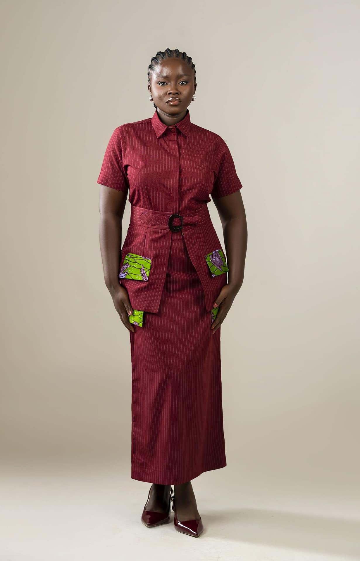 Three looks, one statement. The Nuna Set in burgundy pinstripes features a short-sleeved shirt, matching skirt, and detachable belt overlay for polished, versatile dressing.